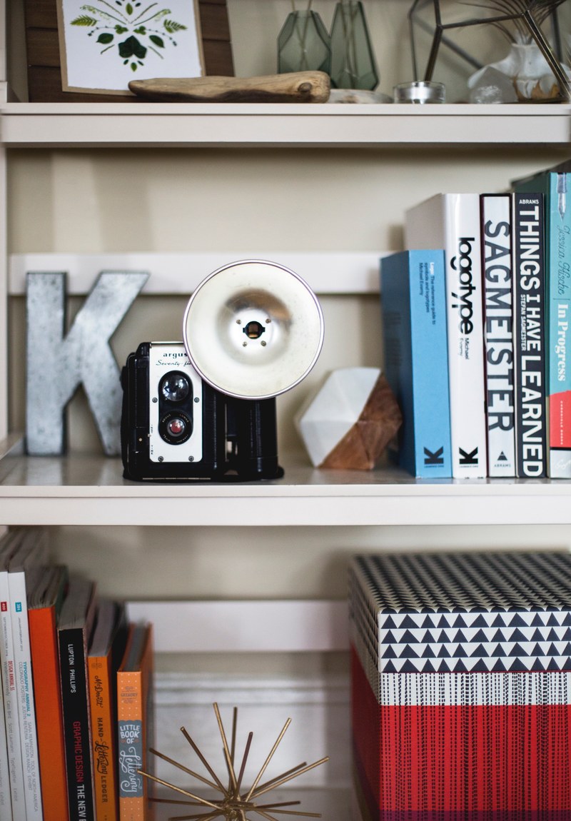 a vintage camera on a shelf lined with books and trinkets, vintage camera on a shelf 4k