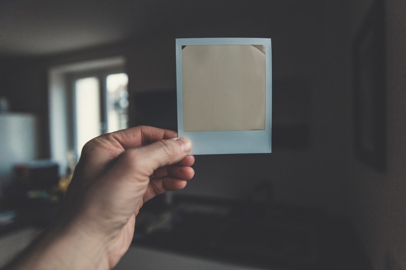 a person holding an exposed piece of polaroid film in their hand, exposed polaroid film 4k