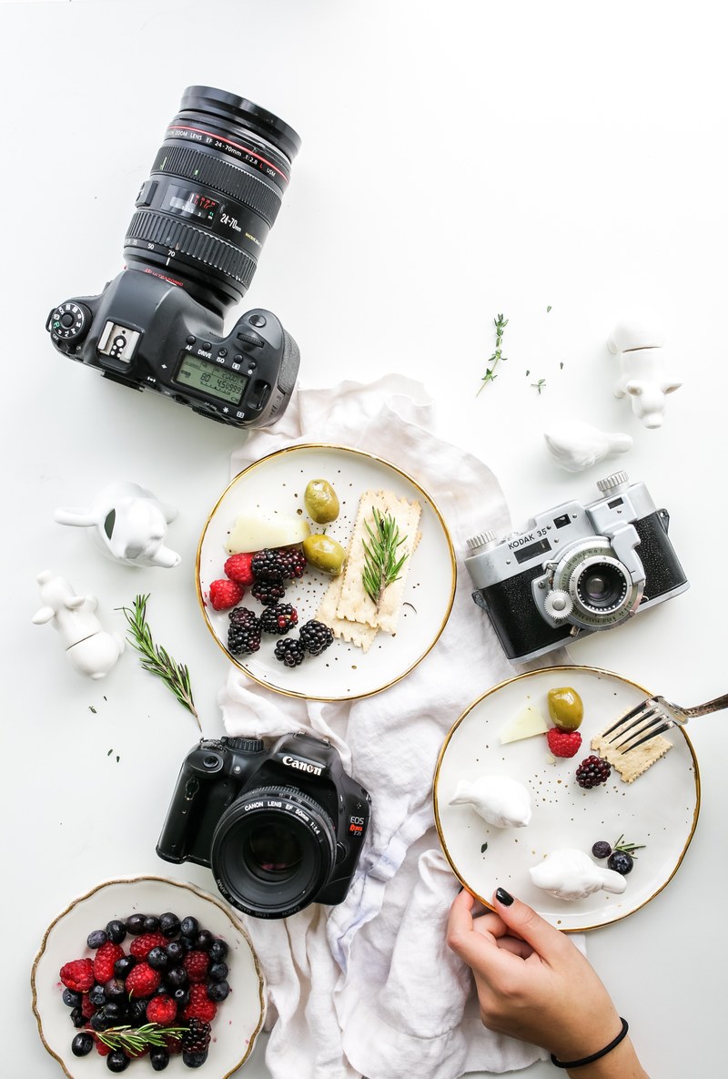 an overhead shot of plates with fruit and crackers and various cameras, food photographer 4k