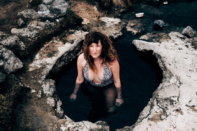woman in a swimsuit standing in a natural hot spring, hot spring bath 4k