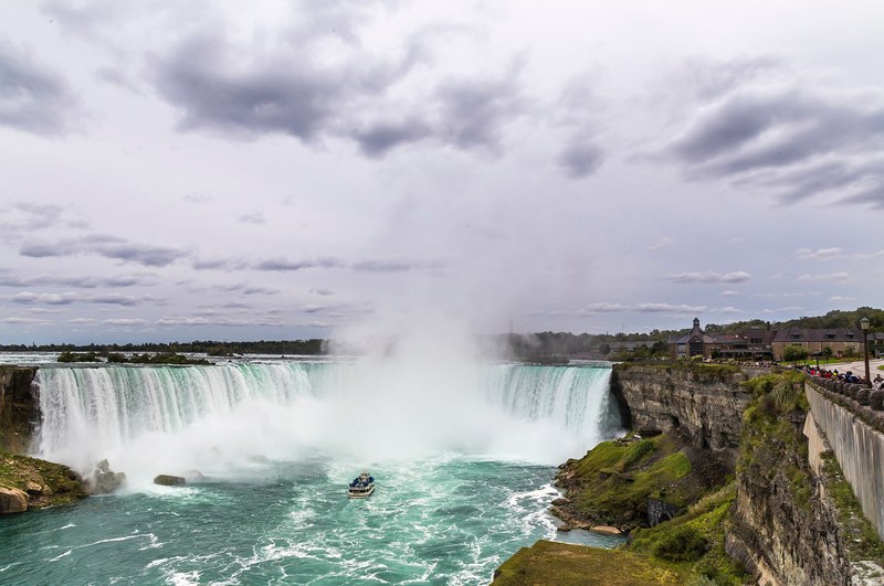 an impressive waterfall tumbling down from a rock face next to a town in niagara falls, niagara falls 4k