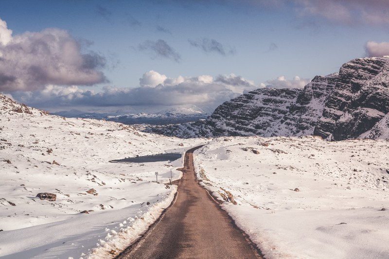 a clean road traveling through complete snow covered fields and mountains n bealach na ba viewpoint, the pass 4k