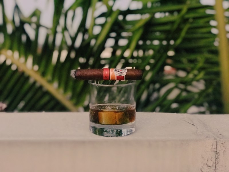 a cigar on top of a glass of whiskey on a white ledge, whiskey amp cigar at sunset 4k