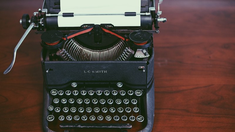 an old black lc smith typewriter on a wooden surface, vintage black typewriter 4k