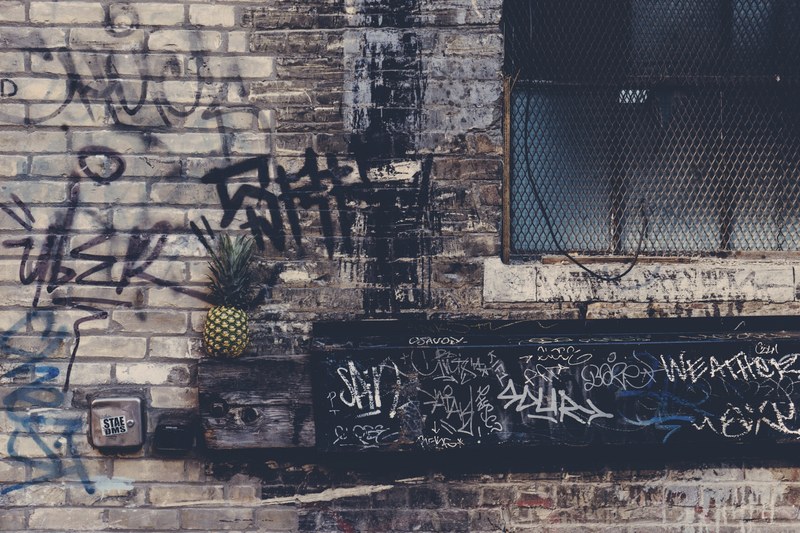 a small pineapple against the brick wall of a building filled with graffiti, _pineapple and graffiti 4k