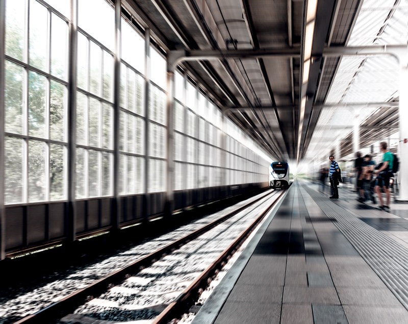 a blurry shot of a train arriving at a railway station with people waiting on the platform, blurry railway platform 4k