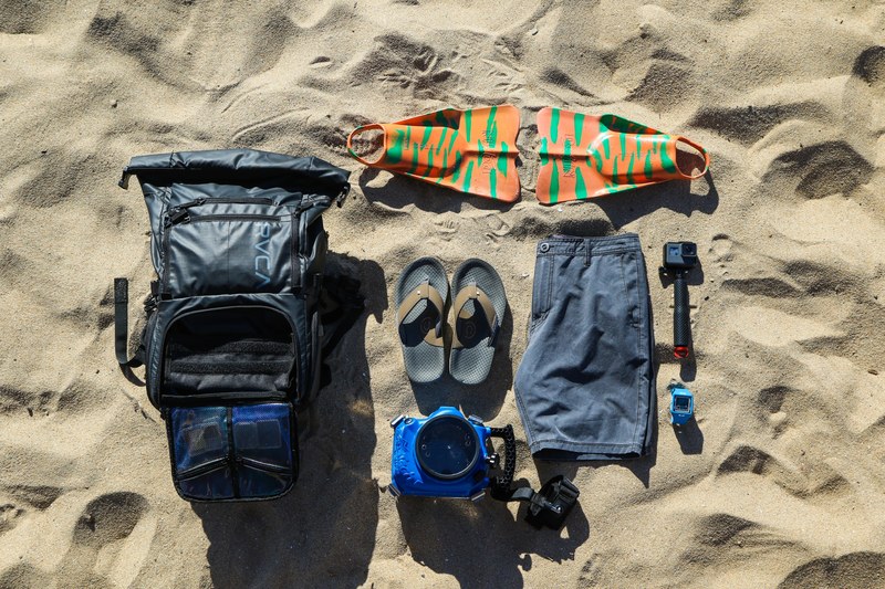 backpack shorts flippers fins underwater camera and a gopro at the sand beach, backpack contents on the beach 4k