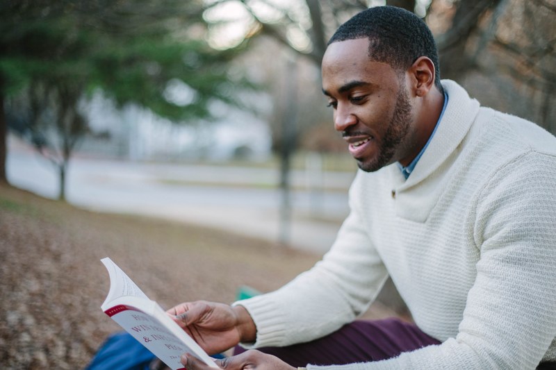a man reading a book while sitting in a park in atlanta during fall, reading in atlanta 4k