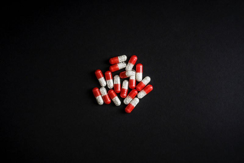 a pile of red and white capsules with a black background, _drugs 4k