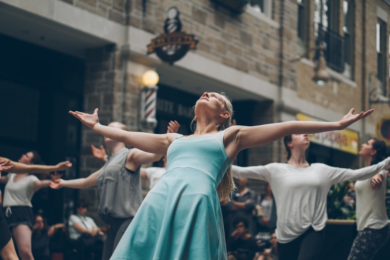 a crowd dances in the street in guelph with their arms spread looking upward, crowd dancing in the street 4k
