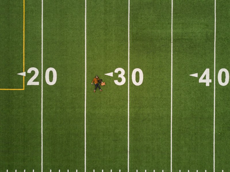 drone aerial view of a person lying on the back on a football pitch in montreal, under 30 4k