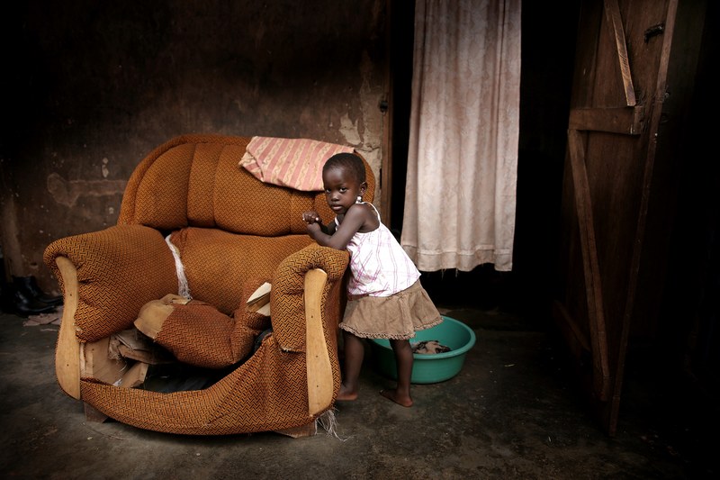 a little girl leaning against an old broken couch that has no cushions in a house in kampala, precious soul 4k