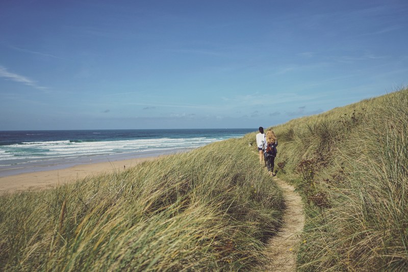 two women walking on the path through the grass coastline in perranporth england united kingdom, perranporth england walk 4k