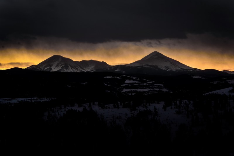 silhouettes of snow covered mountains against the orange sunset sky in silverthorne, setting sun behind mountains in silverthorne 4k