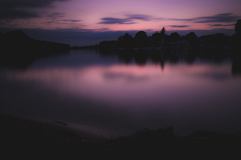 the sunset casting a purple reflection at twilight in the mggelsee lake berlin germany, stalemate 4k