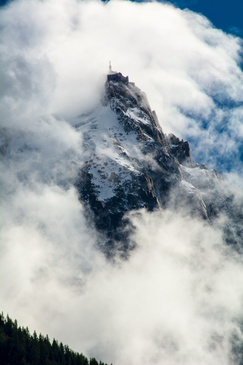 a craggy alpine summit shrouded by white clouds, misty mountain 4k