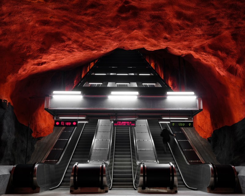 bottom view of escalator in underground metro station underneath red rock ceiling, solna centrum station 4k