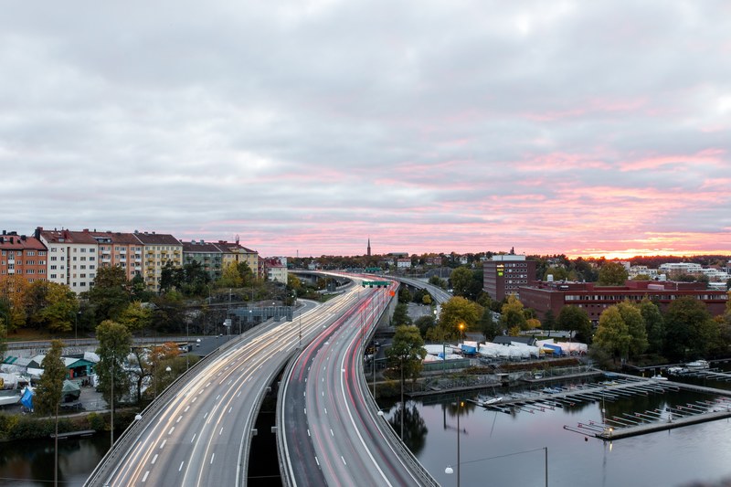 a high shot of light trails on a freeway leading into a quiet town, light trails in a small town at dusk 4k