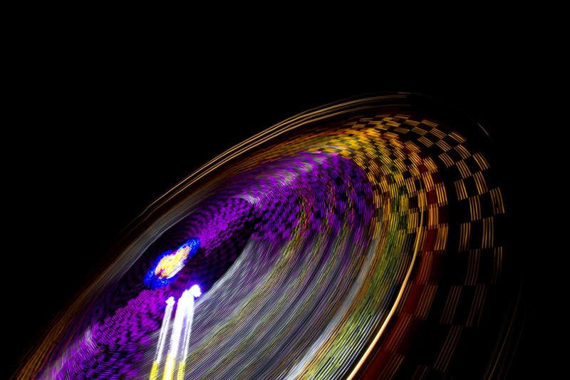 a blurred shot showcasing colorful light trails from a spinning amusement park ride, fairground ride in motion 4k