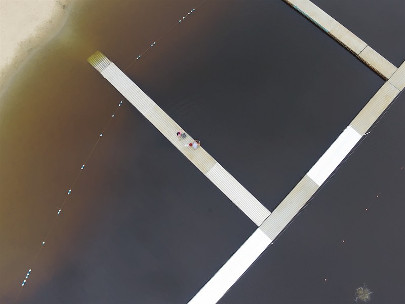 drone view of people on the pontoon boardwalk beach dock at north beach hale reservation, droning at a pond 4k