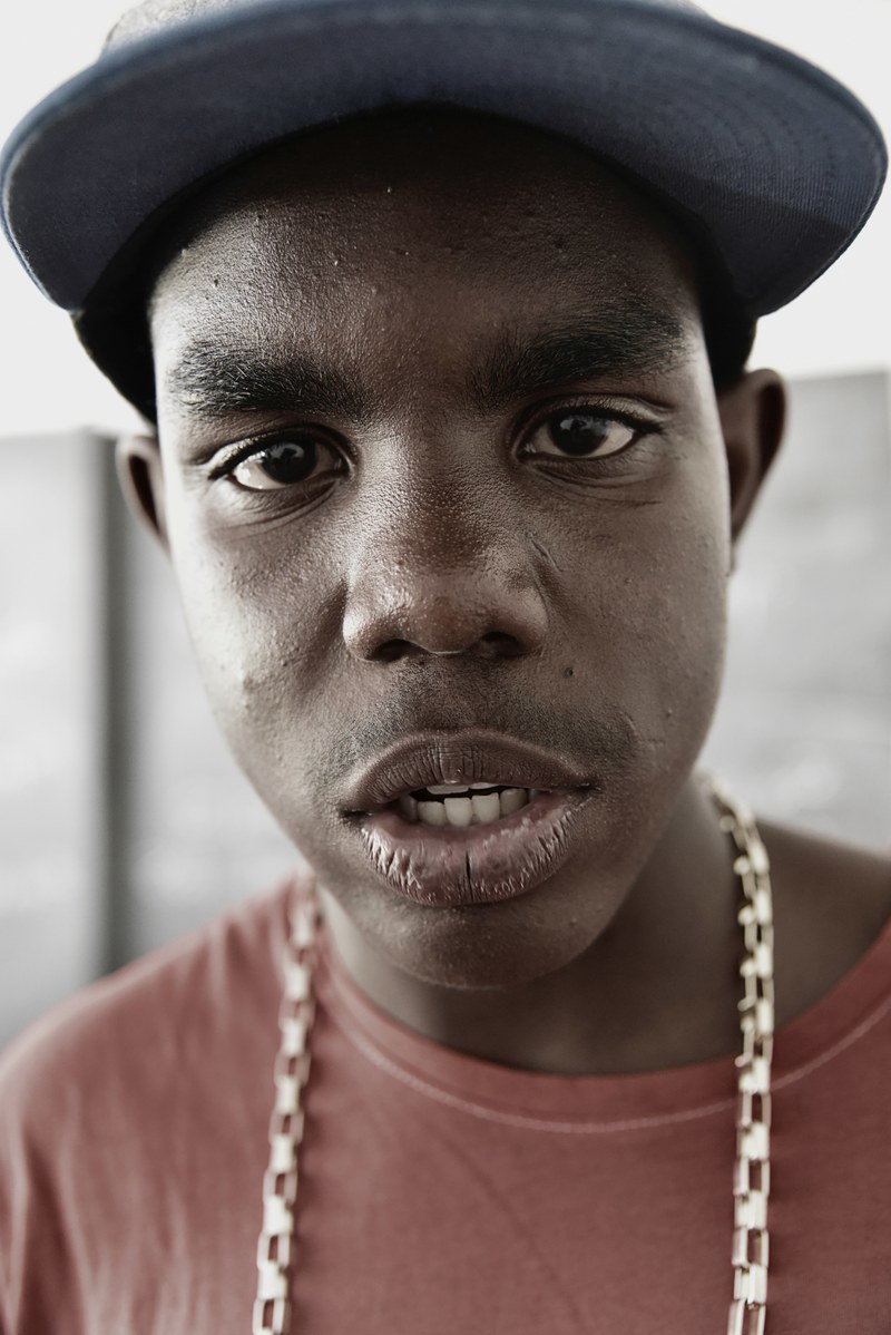 a man wearing a baseball cap and chain looks at the camera against a blurry background, man in cap and chain 4k