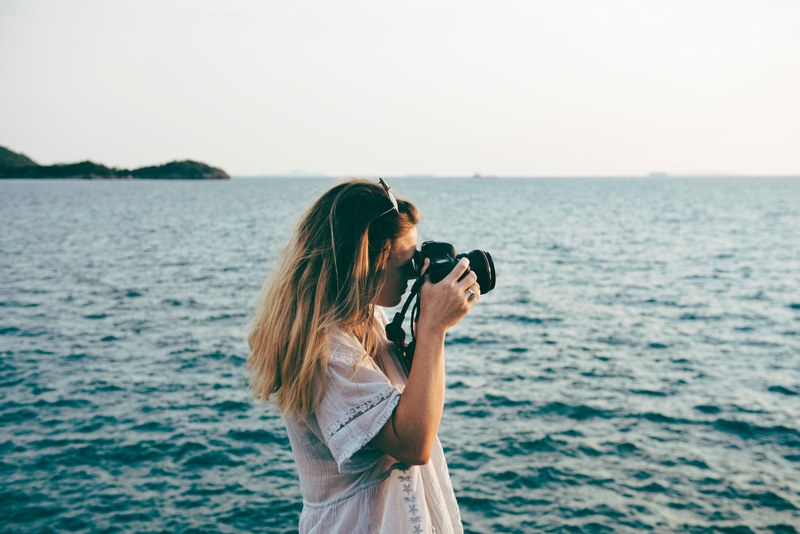 a woman photographing the ocean, photographing the water 4k