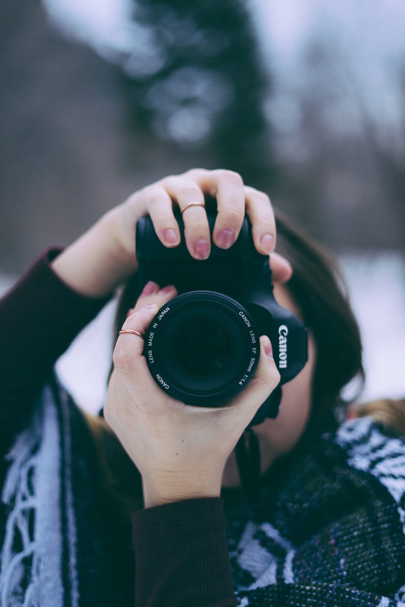 a woman taking a photo with a canon camera in a wintry scenery, photographer in winter 4k