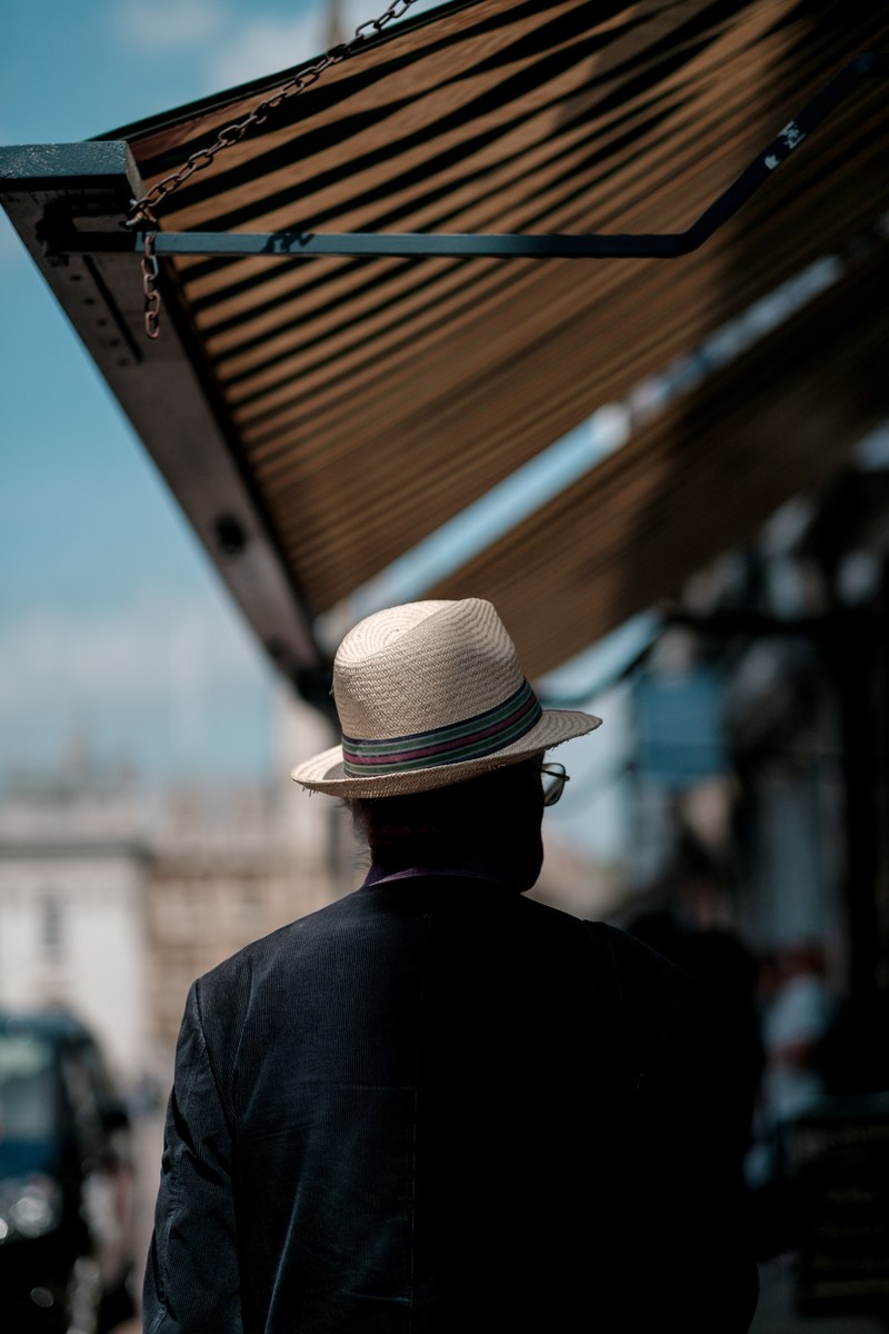 a man in a panama hat on a sidewalk under an awning, man in panama hat on sidewalk 4k