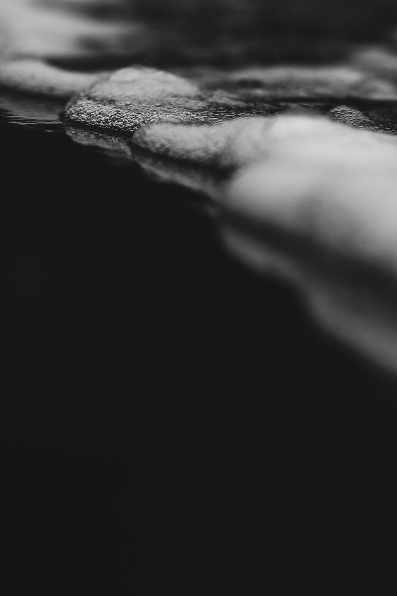 black and white monochrome macro of water and foam texture on surface in piha, black waters of piha 4k