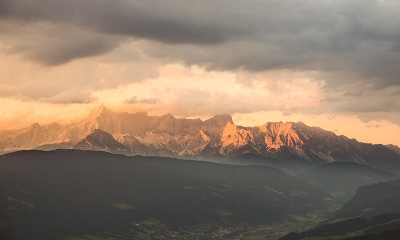a town in a mountain valley with an imposing mountain range at the back, clouds over an austrian mountain valley 4k