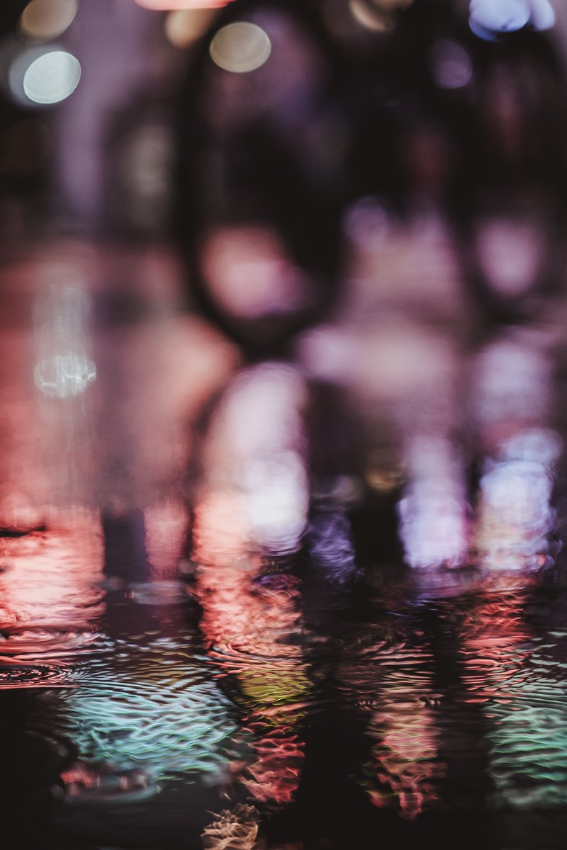 a blurry shot of wet london streets with colored lights reflecting off the ground water, london light 4k