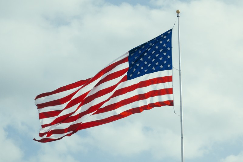 an american flag flaps in the wind on a flagpole, stars and stripes flying high 4k