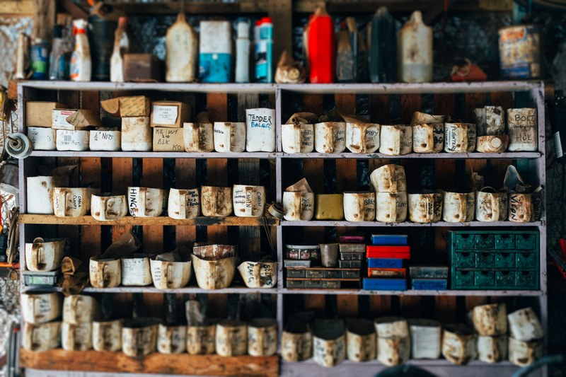 a bookshelf of tools cleaning supplies and labeled mugs and boxes caked in mud and dirt, dirty mug colllection shelf 4k