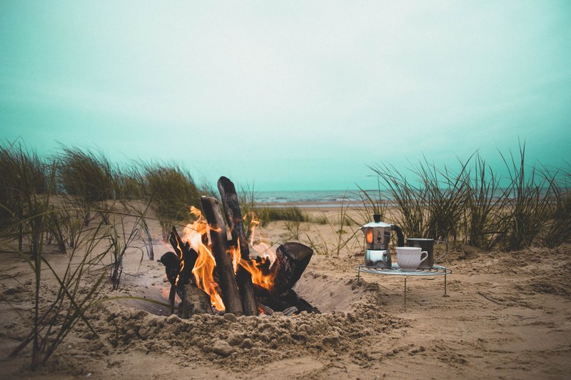 kettle and a cup on a stand by the large fire in the sand hole, fire in the sand hole 4k
