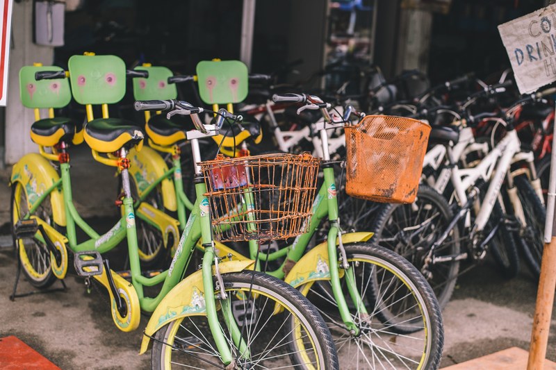 a large number of bicycles parked near a building in pulau ubin, bikes to hire 4k