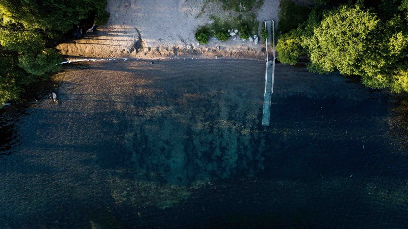 drone aerial view of a small sand beach in the forest, drone view of beach in forest 4k