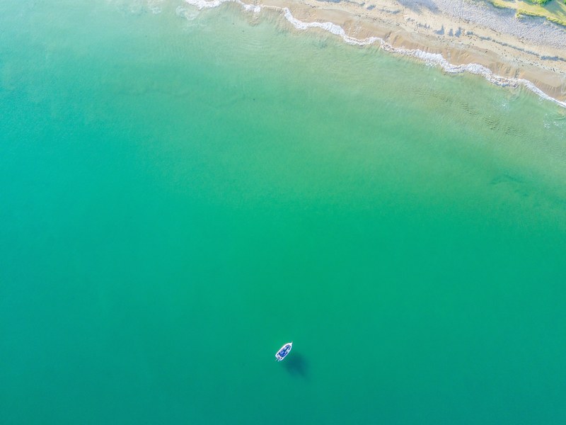 drone aerial view of a boat in the green ocean at te ngaere, drone view of boat in ocean 4k