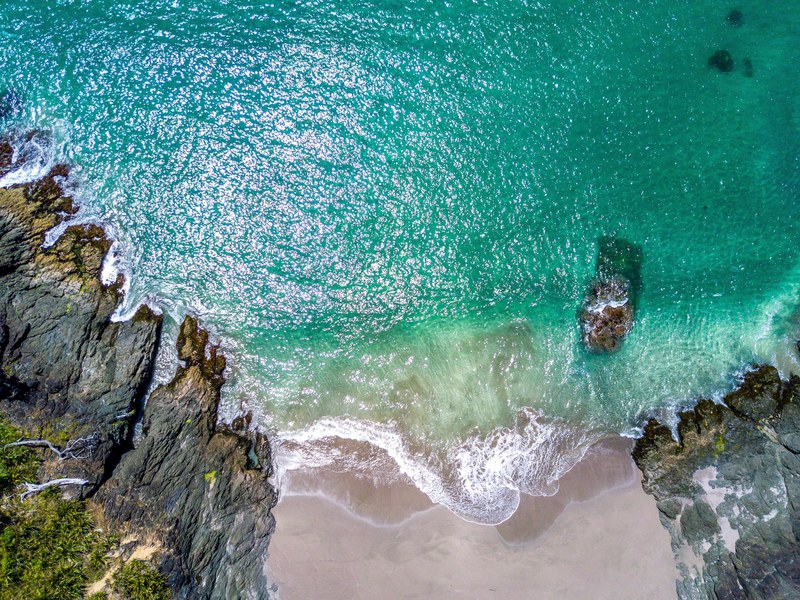 drone view of an ocean washing on sand shore between rocks, drone view of ocean bay 4k