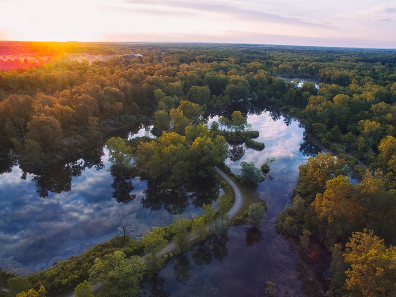 aerial view of a road winding through the rivers of otisville michigan during a golden sunset, otisville river road sunset from above 4k