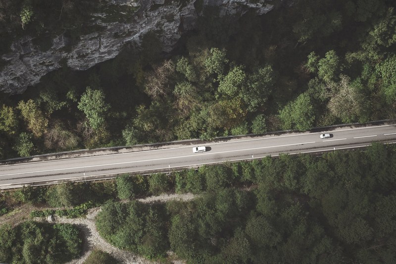 drone shot of two cars on the highway surrounded by hills, _highway drone shot 4k