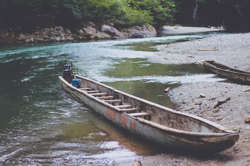 a long canoe on the bank of a quiet stream, canoe on a creek 4k