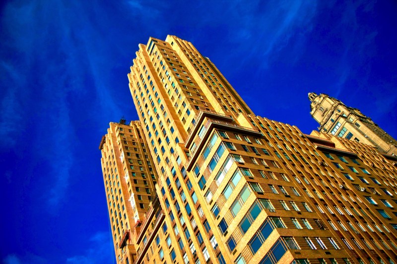 ground view of a brown brick building against a bright blue sky, the skies such a sweet blue 4k