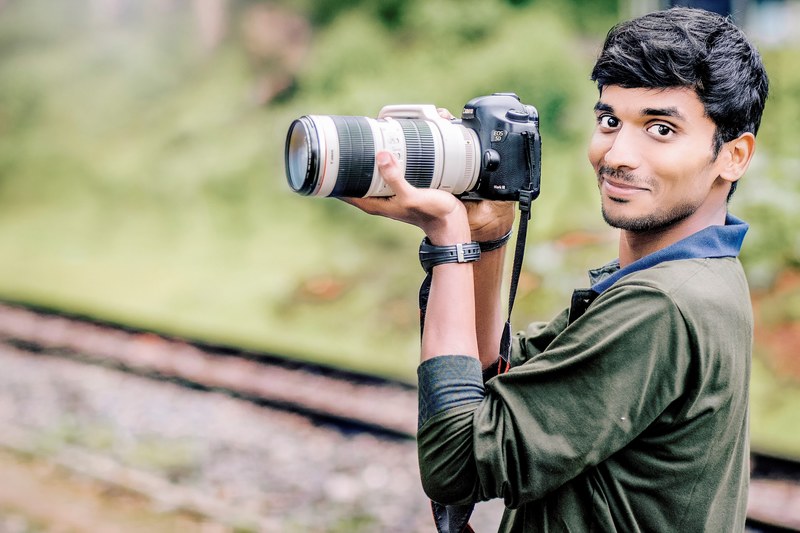 a man holding a canon camera with a large telephoto lens on it in ooty, photography is love 4k