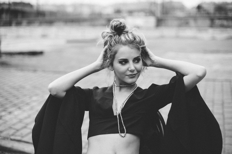 black and white shot of young attractive girl with hair bun and fashionable clothes smiling, girl with hair bun smiling 4k