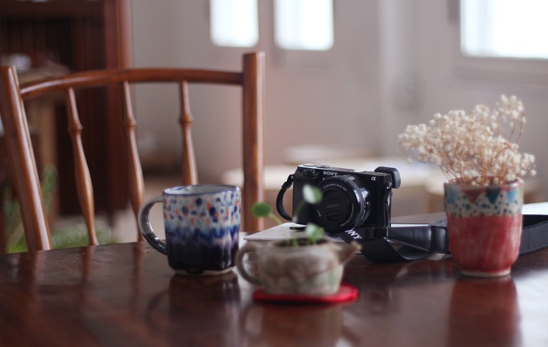 a polka dot mug sony camera and plant on a table a semasa cafe and shop, ceramics cafe camera 4k