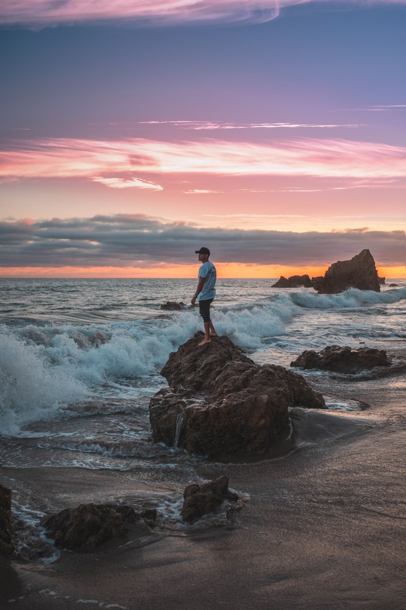 man on rock beach shore and crashing wave hd, 4k