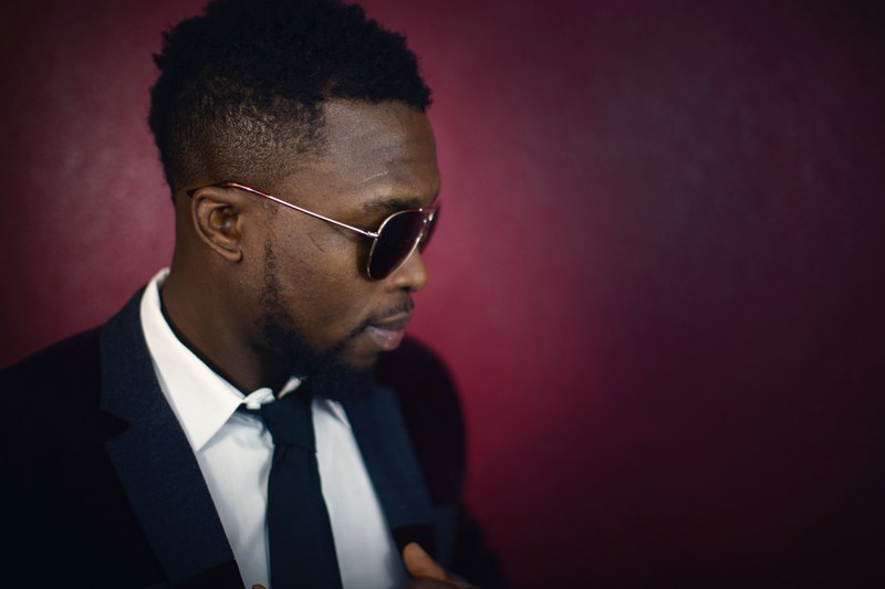 an elegant man in sunglasses against the backdrop of a dark red wall, elegant man near a red wall 4k