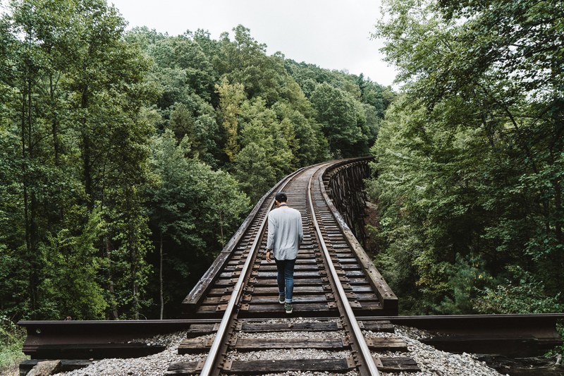 a man walking on elevated railroad tracks, high up on railroad tracks 4k