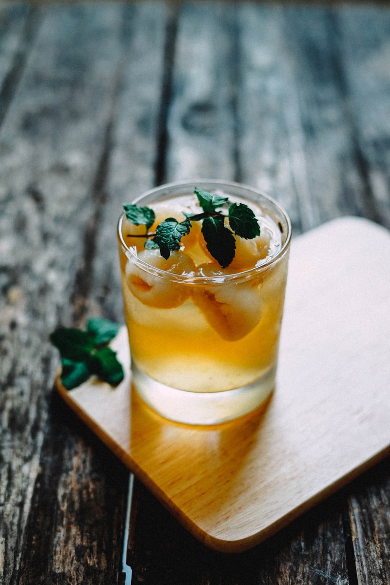 a cold cocktail whiskey with leaves on a table, a cold cocktail whiskey 4k
