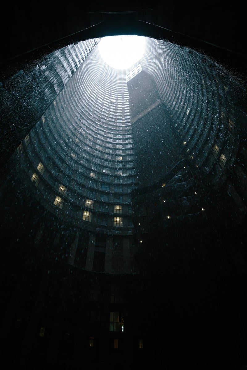 a dramatic shot of the core of the ponte city tower in johannesburg under heavy rain, rain in a skyscraper core 4k